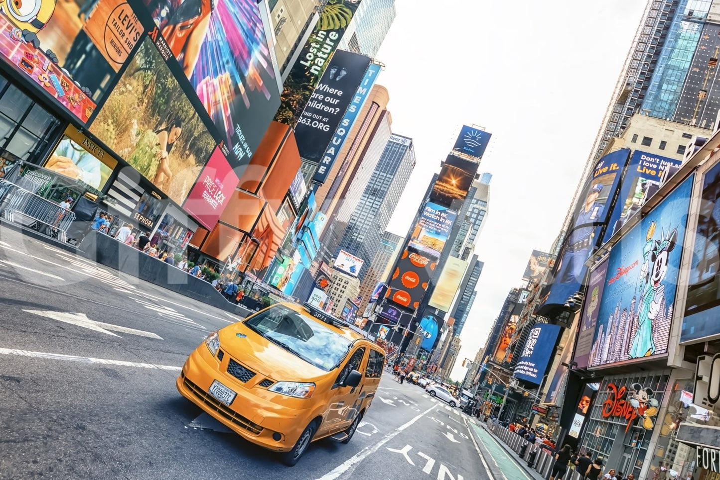 NYC Buzz wallpaper mural shown full-wall with a yellow taxi crossing Times Square amid bright billboards and skyscrapers