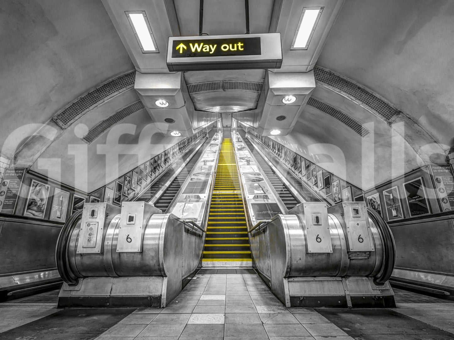Black and white subway scene with yellow escalator