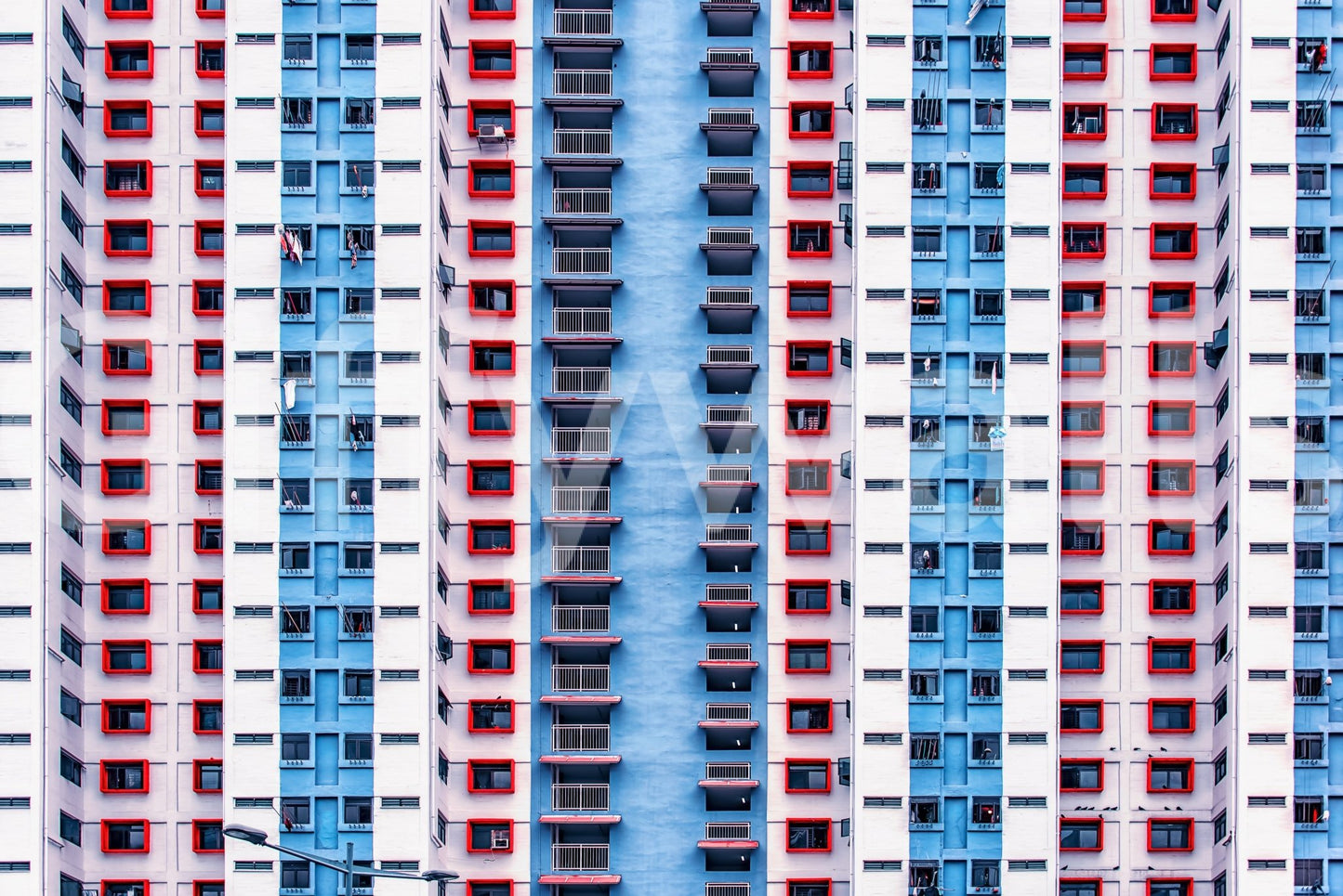 Urban Gridlock wallpaper mural shown as a full-wall facade of repeating red, white and blue apartment windows