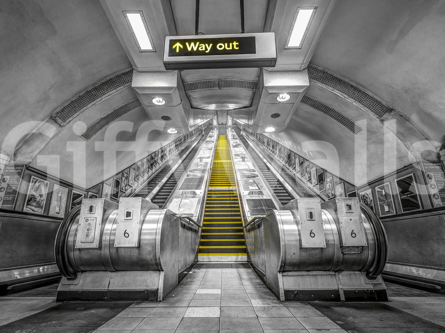 Black and white subway scene with yellow escalator