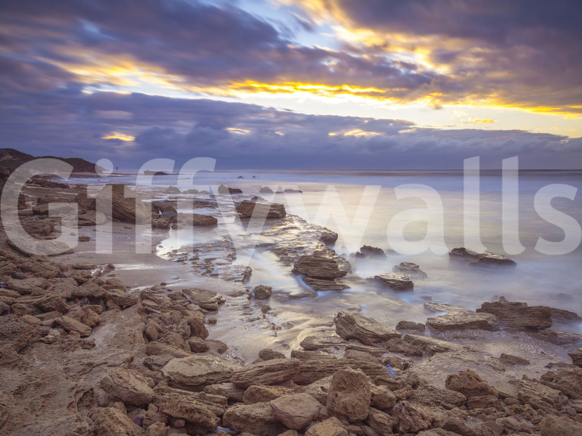Close-up of beach wallpaper swatch with brown rocks, silky water and gold clouds GD14207