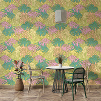 Tropical leaf design in pastel avocado green, pink, and beige on wallpaper.

