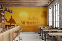 Golden desert wall mural showing silhouettes and distant pyramids