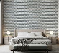 Bedroom dressed in slate blue zellige cross wallpaper over a creamy ground
