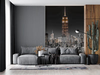 A grey living room sofa faces outward from the illuminated skyscraper NYC wall mural.