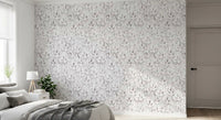 Grey botanical foliage wallpaper in a bedroom with a soft grey throw and floor lamp GD12337