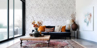 Muted grey botanical foliage wallpaper behind a navy velvet sofa with orange cushions GD12337