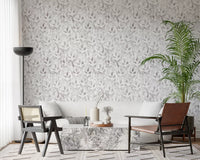 Muted grey foliage wallpaper in a living room with a cream sofa and cane armchairs GD12337