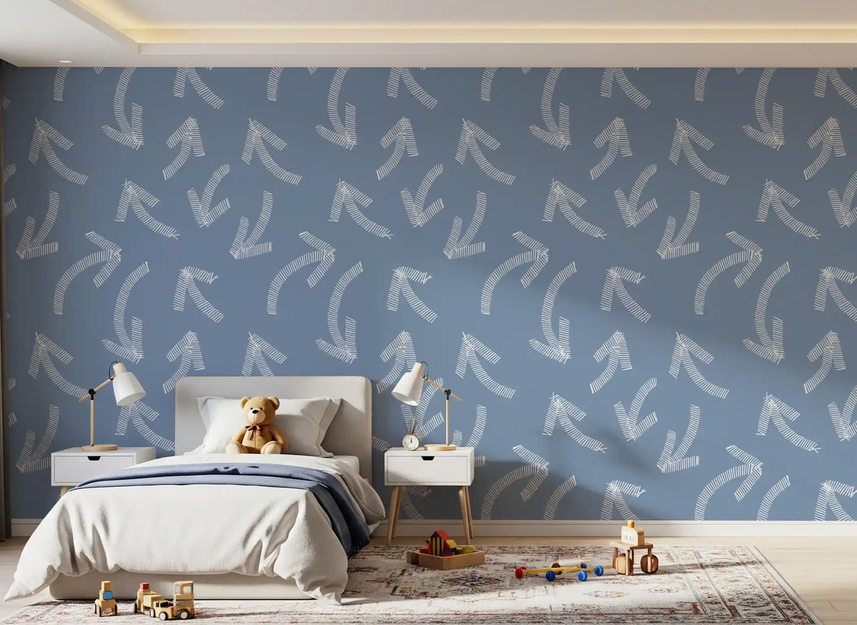 Muted blue scribble arrows wallpaper behind a child's bed with teddy and bedside lamps GD12470