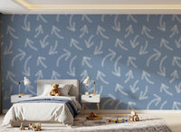 Muted blue scribble arrows wallpaper behind a child's bed with teddy and bedside lamps GD12470