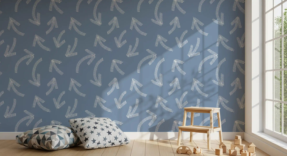 Blue scribble arrows wallpaper in a nursery corner with star cushions and wooden toys GD12470