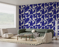 Abstract geometric wallpaper in a living room with a sage green sofa and cream lounge chair GD12480