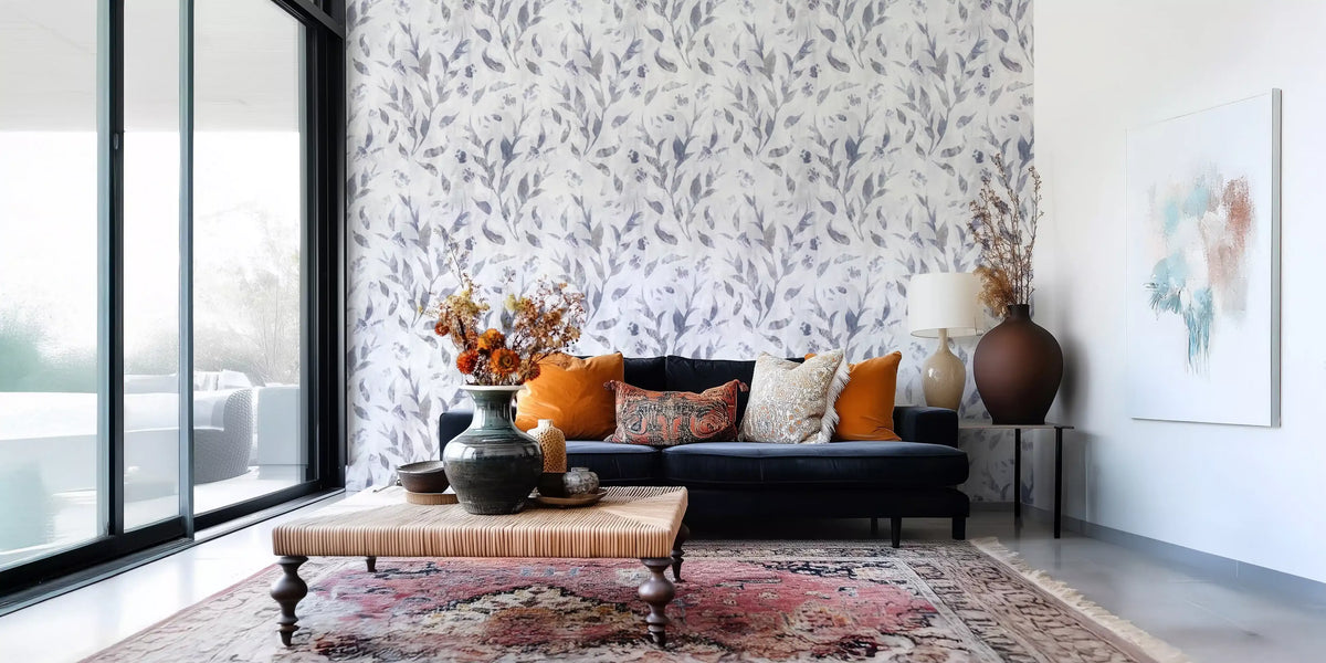Watercolor willow branches wallpaper behind a navy sofa with orange cushions in a bright living room GD12681