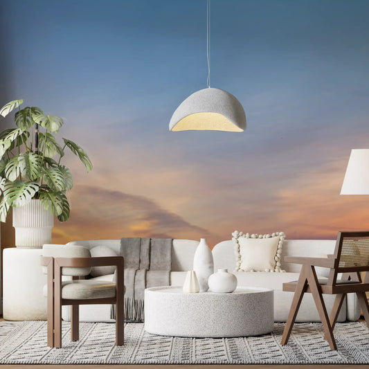 Sunset sky wall mural above a cream sectional sofa and round pouf table GD12809