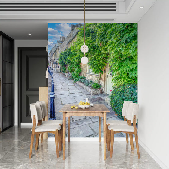 Stone path and climbing ivy mural behind a wood dining table with cream chairs GD12849