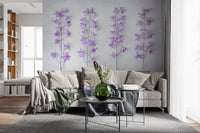 Lilac delphinium wallpaper behind a gray sofa with black side tables and a bookshelf GD13138