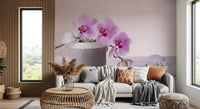 Pink orchid wallpaper above a cream sofa with patterned cushions and a rattan side table GD13139