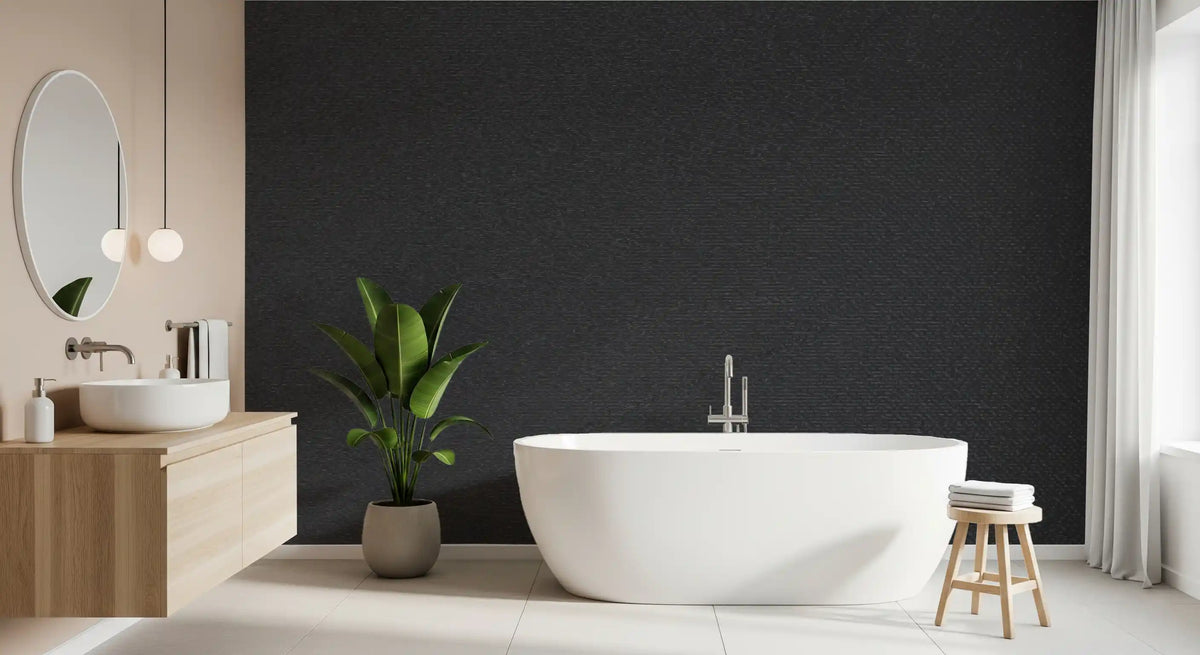 Charcoal wallpaper in a bathroom with a white freestanding tub, wood vanity and round mirror GD13178