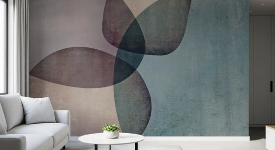 Abstract wallpaper mural with blue and mauve petal shapes behind a light gray sofa and small white table GD13382