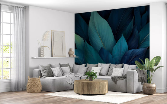 Tropical wallpaper mural of teal leaves behind a grey sectional and round wood table GD13821