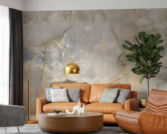 Marble wallpaper behind a tan leather sofa, a brass arc lamp and a round wood coffee table GD13992