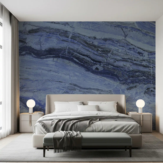 Blue marble wallpaper behind a gray upholstered bed and bench in a calm bedroom GD13996