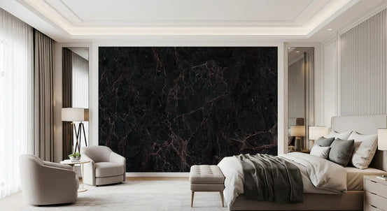 Black marble wallpaper behind a bed with gray throws, a bench and cream armchairs GD14024