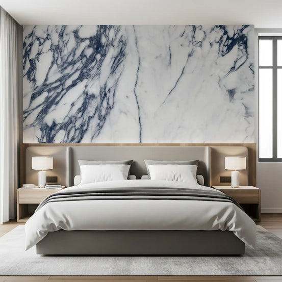 Marble wallpaper mural behind gray upholstered bed, striped duvet and table lamps GD14110
