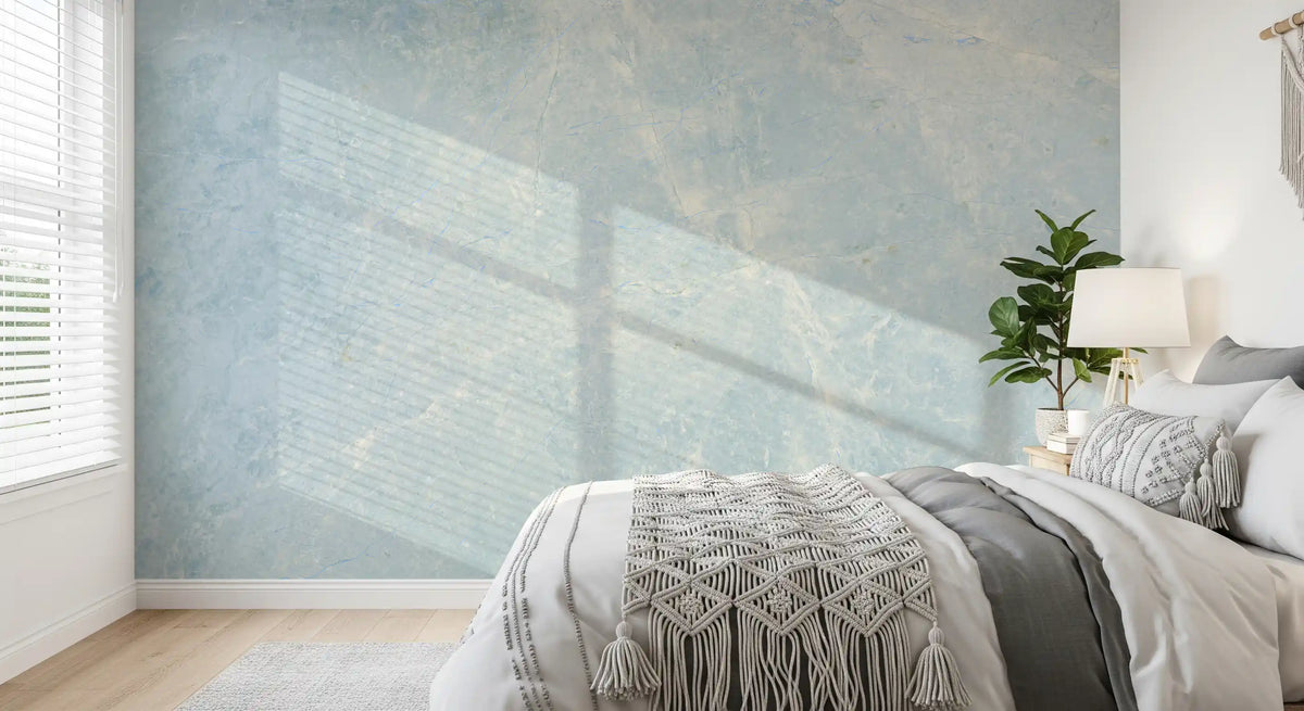 Bedroom with white bed, macrame throw and window light across a blue marble wall GD14187