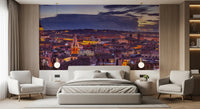 Bedroom with upholstered bed and two cream armchairs below a Roman dusk skyline GD14206