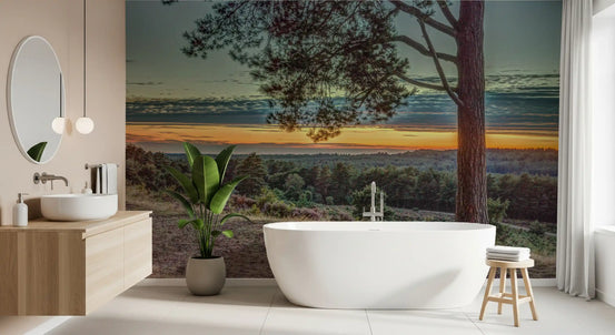 Forest wallpaper behind a freestanding white tub and wooden vanity in a bathroom GD14212