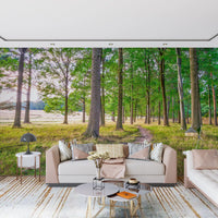 Blush pink sofa and round glass coffee table in front of a green forest path wall mural GD14219