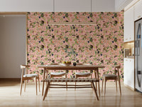 A Primate's Garden Party pink wallpaper behind a wooden dining table and bench with cane chairs