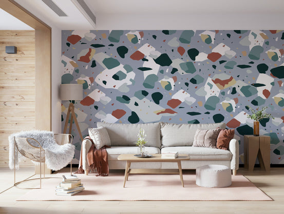 Confetti Stone wallpaper mural in grey terrazzo with terracotta and teal behind a cream sofa in a living room