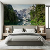 Alpine Reflections wallpaper mural of the mirrored mountain lake behind a grey upholstered bed in a calm bedroom