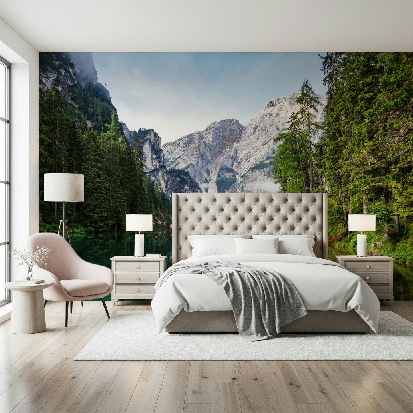 Alpine Reflections wallpaper mural of grey peaks and pine forest behind a tufted grey bed and pink chair in a bedroom