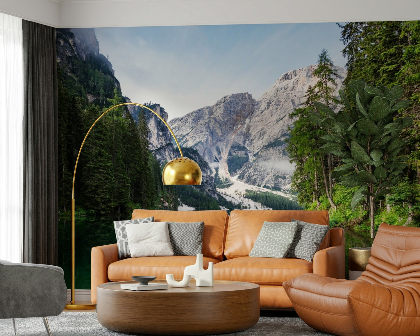 Alpine Reflections wallpaper mural of grey peaks and pine forest behind a caramel leather sofa in a living room