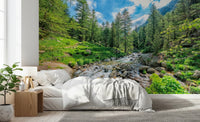 Alpine Stream wallpaper mural of a mountain creek behind a white bed with waffle throw in a bedroom