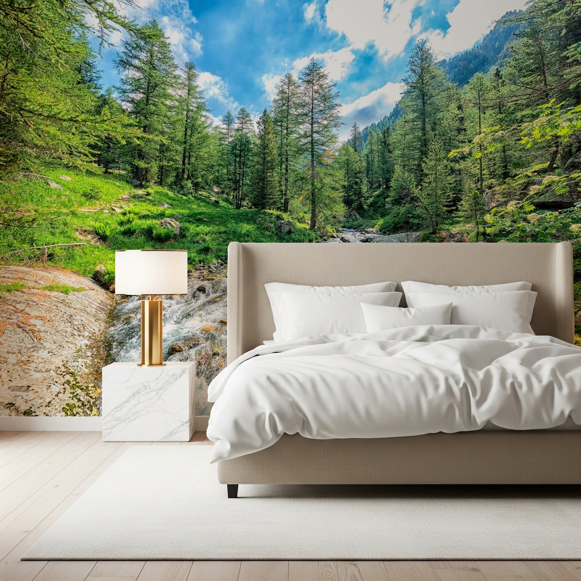 Alpine Stream wallpaper mural with a mountain creek behind a taupe bed and marble nightstand in a bedroom