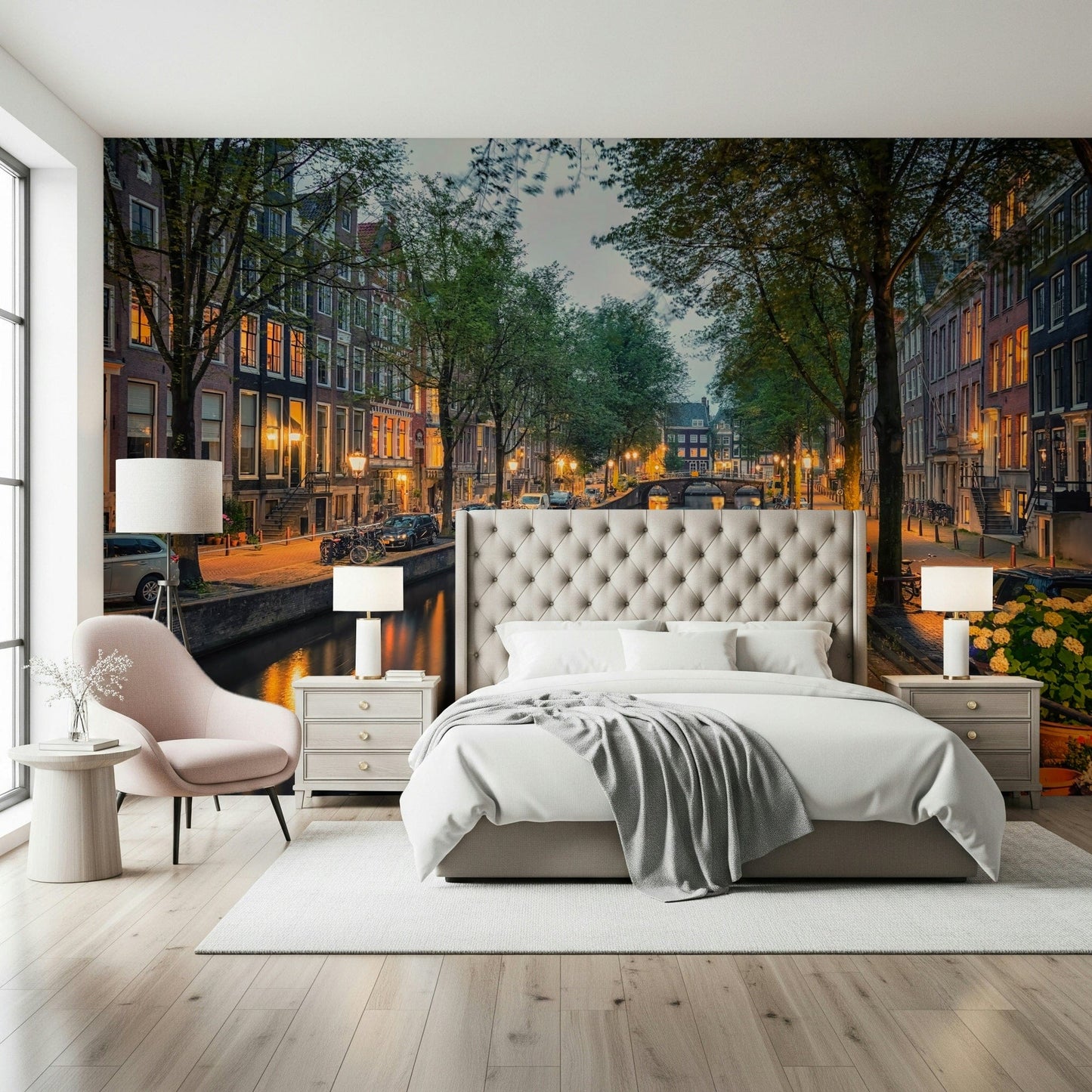 Amsterdam Canal Lights wallpaper mural of a dusk canal above a tufted cream bed with a pink chair in a bedroom