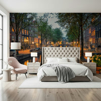 Amsterdam Canal Lights wallpaper mural of a dusk canal above a tufted cream bed with a pink chair in a bedroom