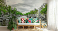 Amsterdam Canal Serenity wallpaper mural of a leafy canal behind a rattan sofa with tropical-print pillows in a sunroom