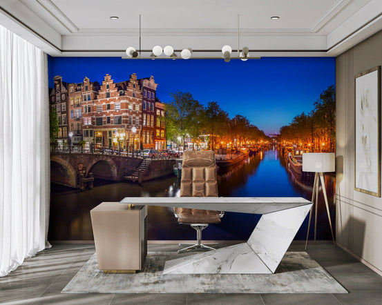 Amsterdam Night Canvas wallpaper mural of a blue-hour canal and lit houses behind a marble desk in a home office