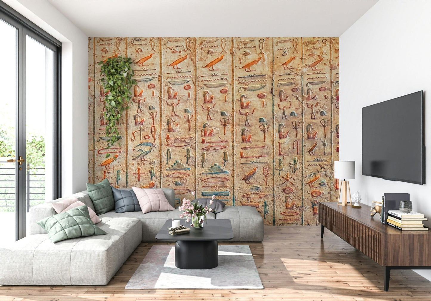 Ancient Glyphs wallpaper mural of carved hieroglyphs behind a grey sectional and wood TV console in a living room