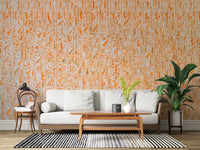 Ancient Inscriptions wallpaper mural in orange glyphs behind a white sofa and potted palm in a bright living room