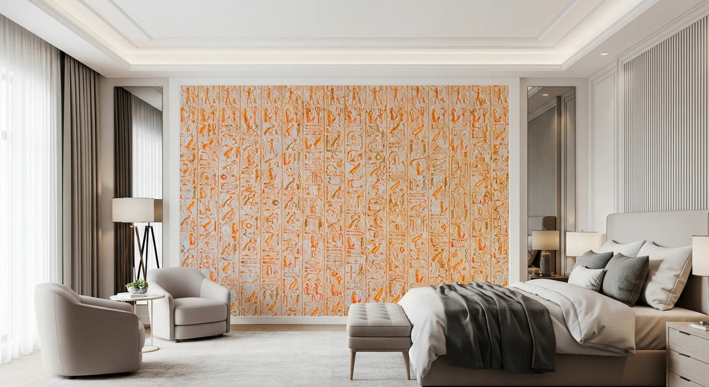 Ancient Inscriptions wallpaper mural of orange Egyptian glyphs on a bedroom accent wall behind a bed and gray armchairs