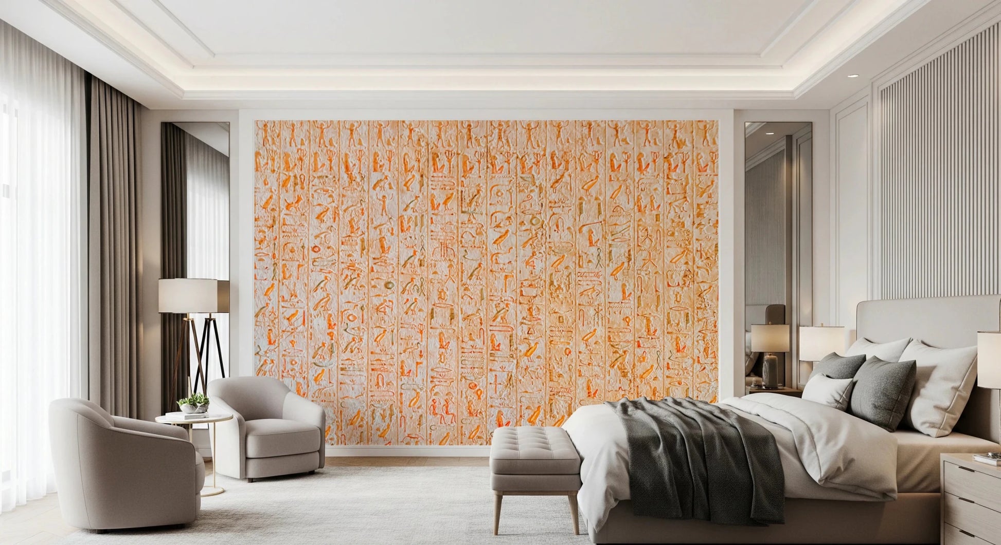 Ancient Inscriptions wallpaper mural of orange Egyptian glyphs on a bedroom accent wall behind a bed and gray armchairs