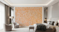 Ancient Inscriptions wallpaper mural of orange Egyptian glyphs on a bedroom accent wall behind a bed and gray armchairs