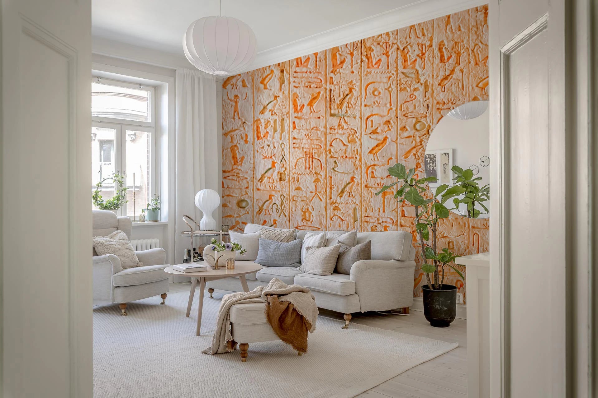 Ancient Inscriptions wallpaper mural of carved orange glyphs behind a gray sofa in a Scandinavian living room
