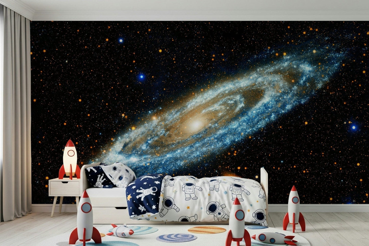 Andromeda mural of a blue spiral galaxy behind a kids bed with astronaut bedding and red rocket toys